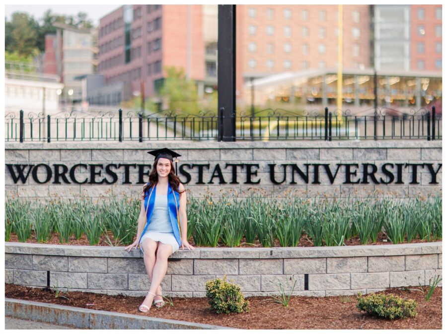 Senior girl sitting in front of Worcester State University sign