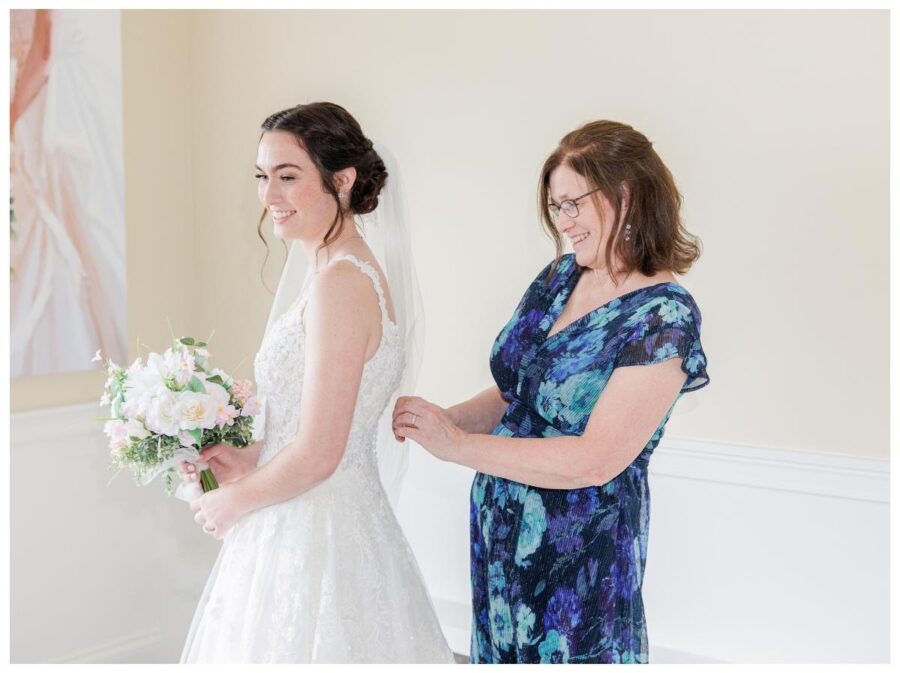 Mother of the bride buttoning bride into dress at Pleasant Valley Country Club Sutton, MA