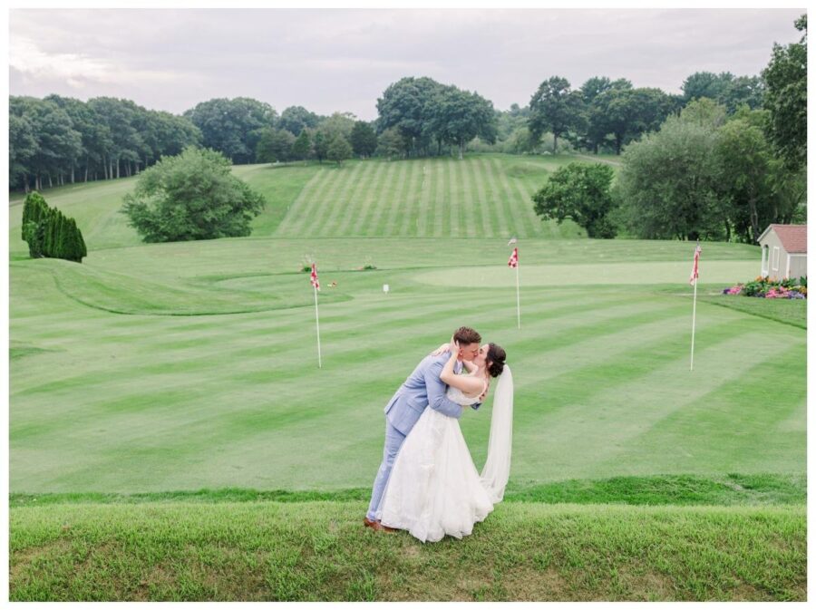 Bride and groom sharing a kiss in front of the golf course during their wedding at Pleasant Valley Country Club Sutton, MA