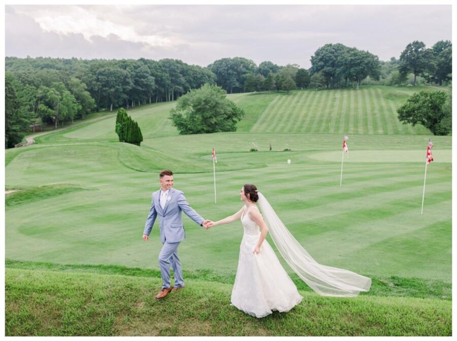 Groom leading bride in front of the golf course during their wedding at Pleasant Valley Country Club Sutton, MA
