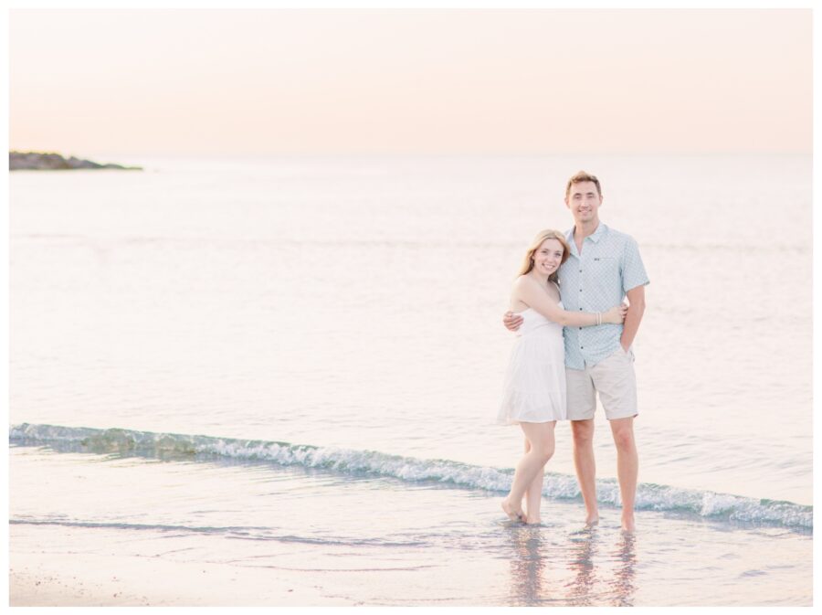 Couple hugging and standing in the ocean at Wingaersheek Beach Engagement session in Gloucester, MA