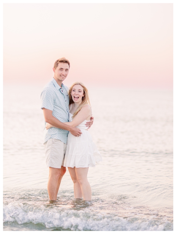 Couple standing and laughing in water at Wingaersheek Beach Engagement session in Gloucester, MA