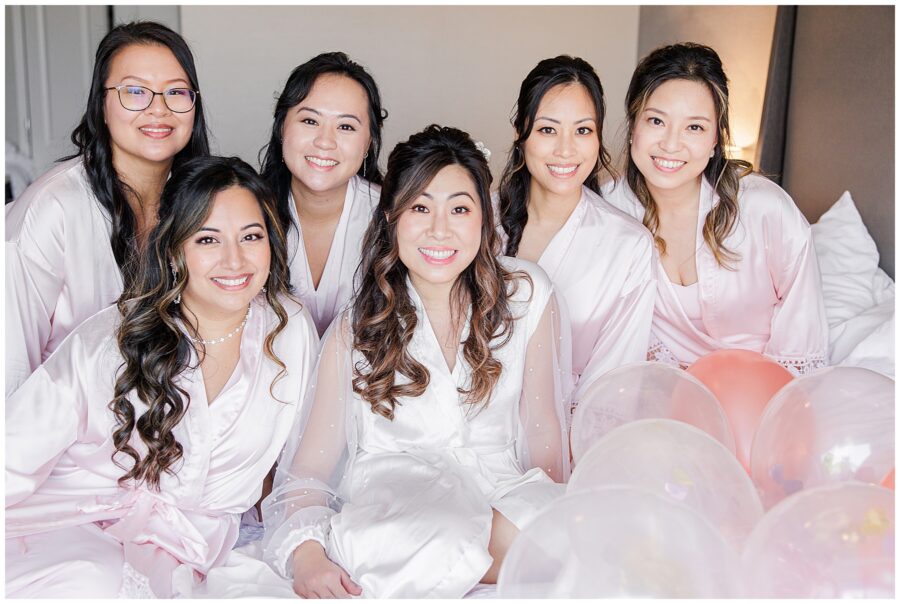 Bridal party in getting ready roves sitting on a bed