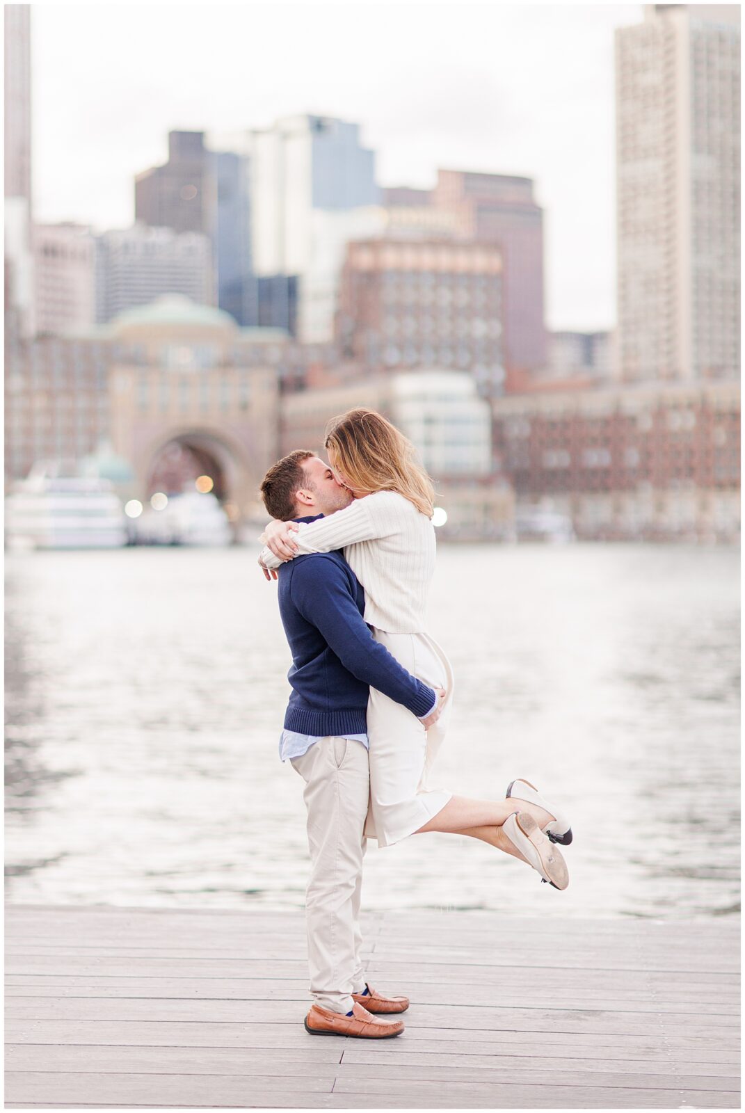 Man picking up and kissing woman during Boston Seaport engagement session. 
