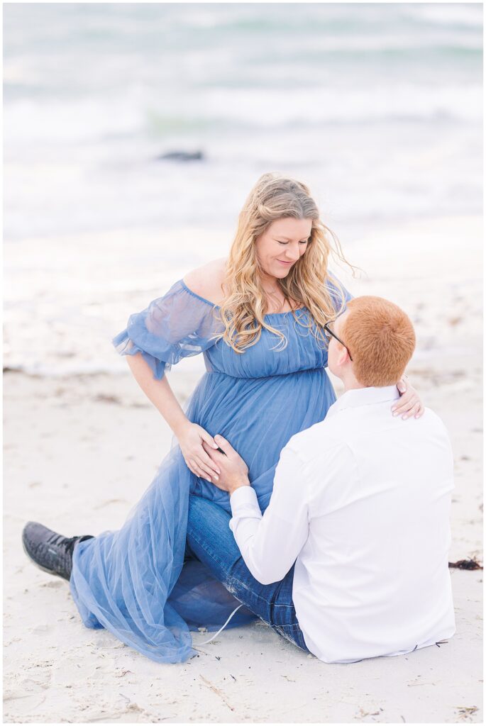 Woman and man sitting on the beach while they hold her baby bump Cape Cod maternity photos
