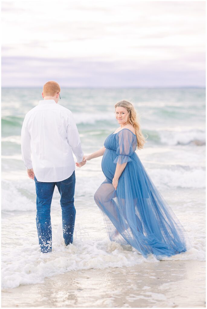Man and woman walking into the ocean at Old Silver Beach in Falmouth, MA for Cape Cod maternity photos