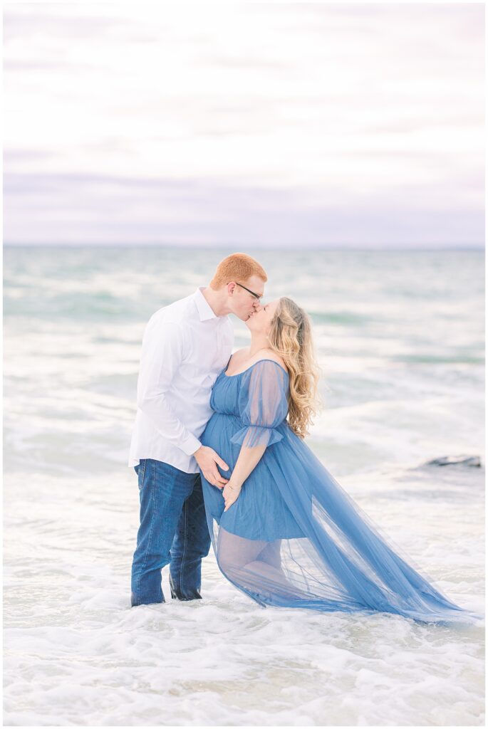 Man and woman kissing in the ocean at sunset for Cape Cod maternity photos