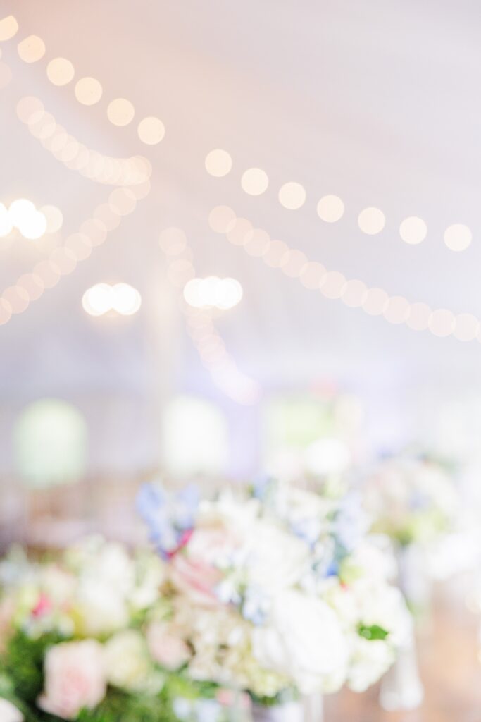 Blurry wedding florals and tent lights representing romantic Cape Cod wedding photography