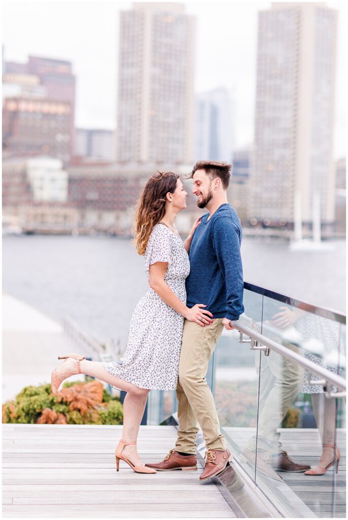 Couple hugging and leaning against a wall at Fan Pier Park during their Boston engagement photos