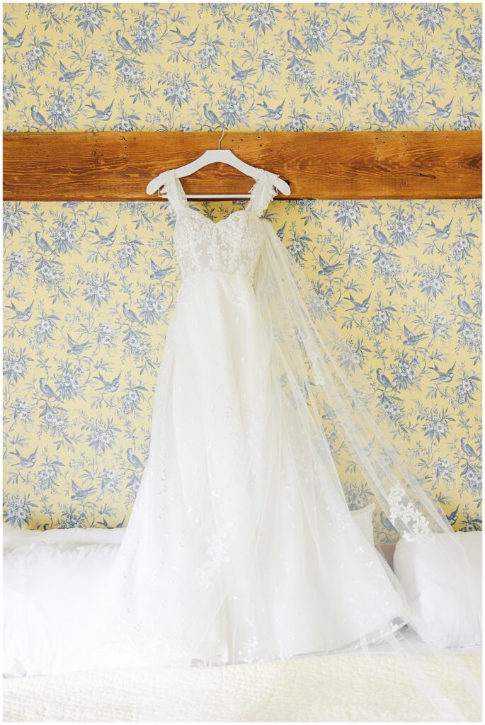 Wedding dress hanging on a wooden beam in a wedding getting ready suite at the Bedford Village Inn