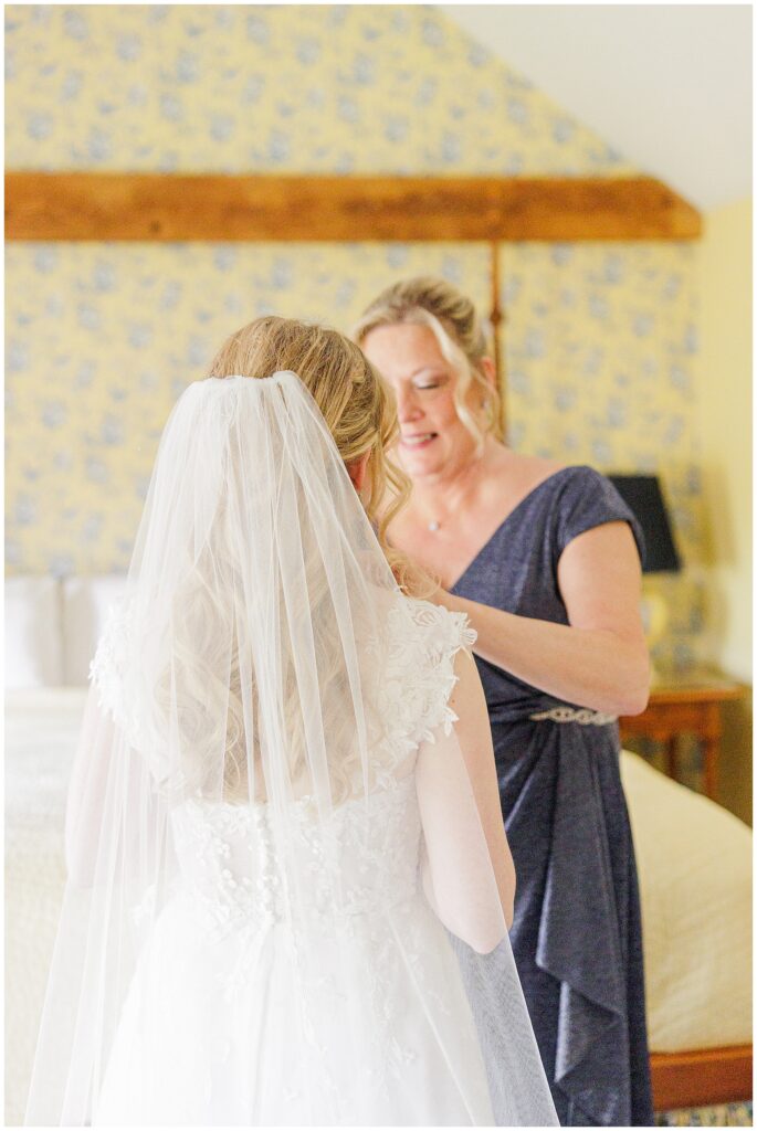 Mother of the bride putting a necklace on the bride representing New Hampshire wedding photography