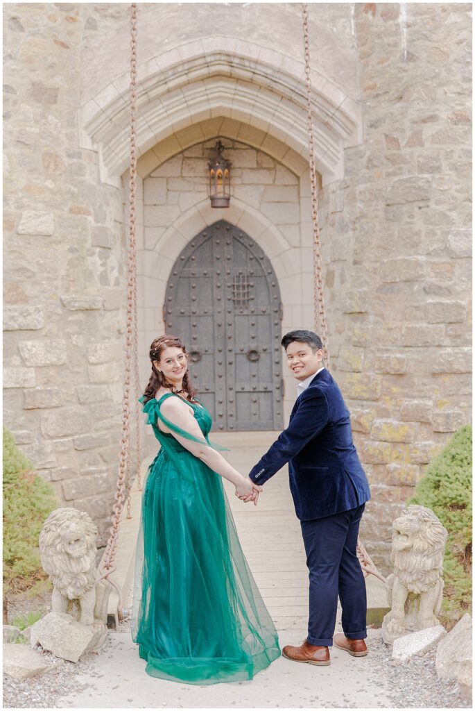 Couple holding hands in front of a drawbridge during their Hammond Castle engagement pictures