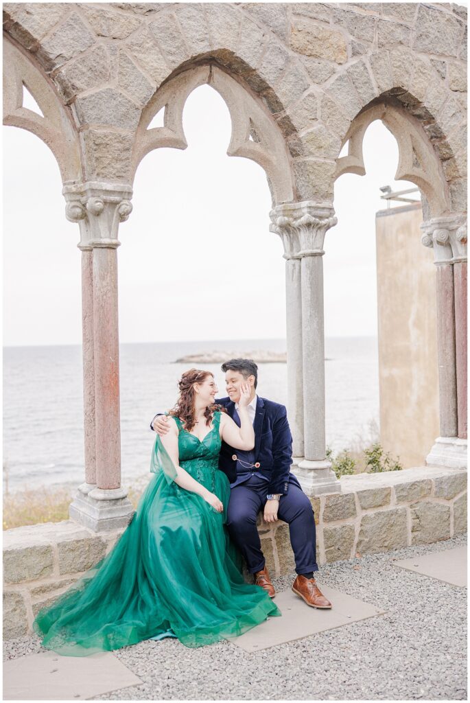 Couple sitting and cuddling in the window arches during their Hammond Castle engagement photos