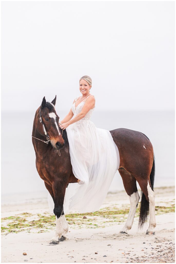 Bride riding her horse and smiling at Old Silver Beach in Falmouth, MA