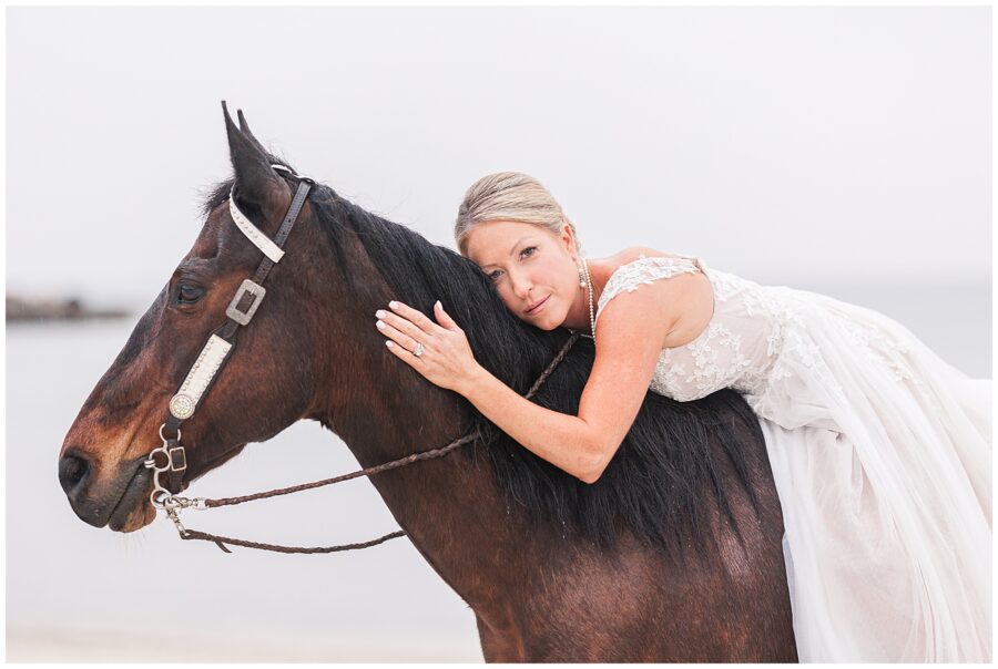 Bride lying against her horse's mane at Old Silver Beach in Falmouth, MA Cape Cod