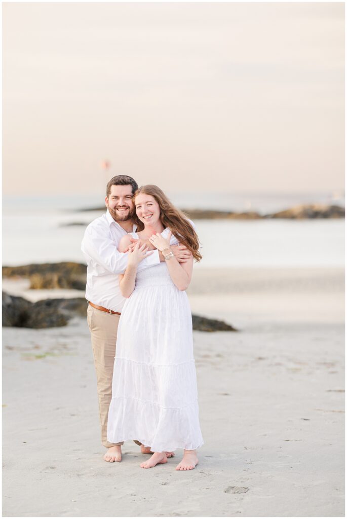 Couple hugging and smiling by rocks at Wingaersheek 