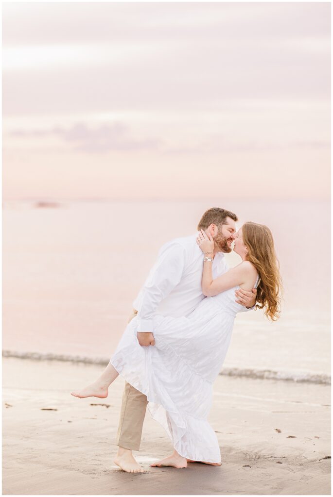 A man dipping a woman and they are about to share a kiss at a Gloucester beach