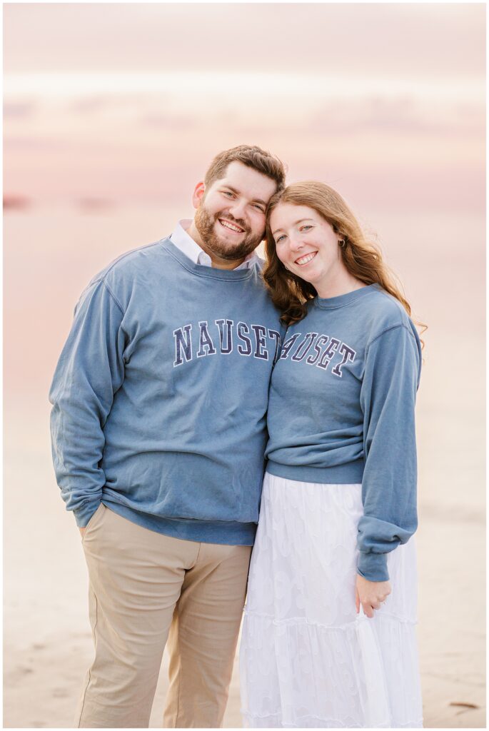 A couple wearing matching Nauset sweatshirts and smiling at the camera