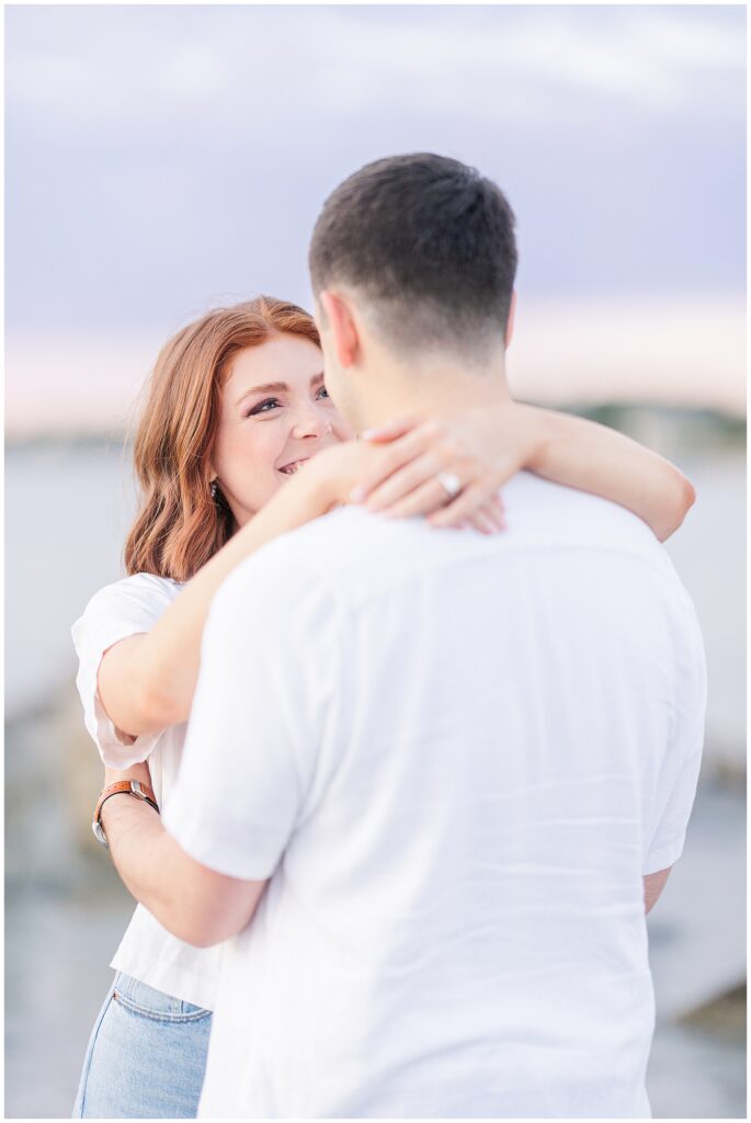 A woman with her arms around a man's neck looks at him lovingly, both smiling and close together