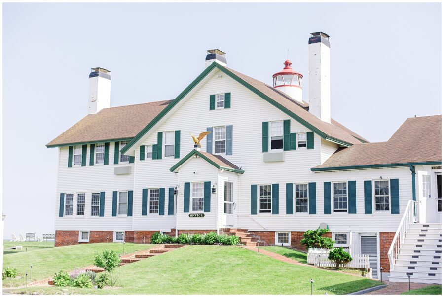 The Lighthouse Inn in West Dennis, MA: A white building with green shutters, a red-roofed lighthouse on top, and a sign that reads “Office” on a well-manicured lawn.