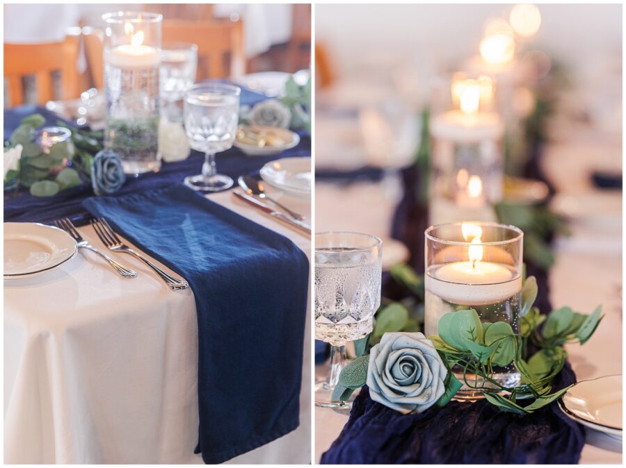 Close-up of a table setting with a blue napkin, glassware, and a candle centerpiece with greenery and blue roses.