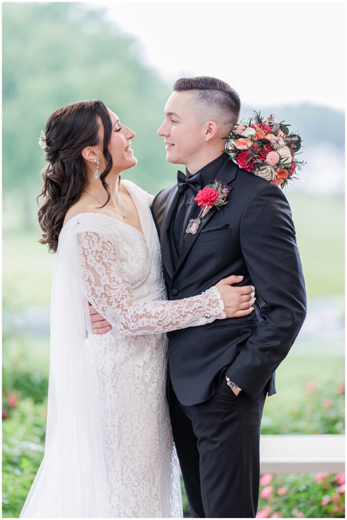 Bride and groom embracing, smiling at each other.