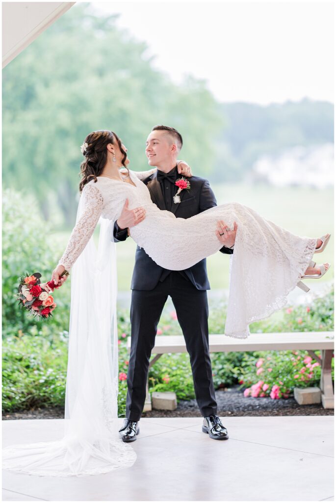 Groom lifting bride while she holds a bouquet at Cape Club of Sharon.