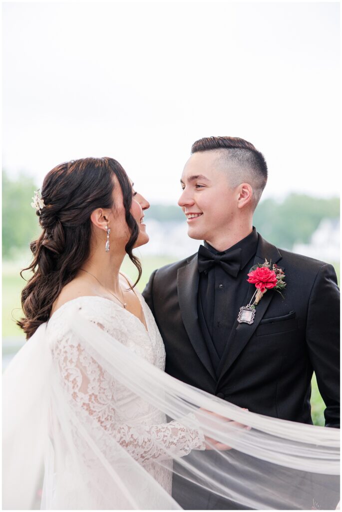 Bride and groom gazing at each other with the bride’s veil flowing.