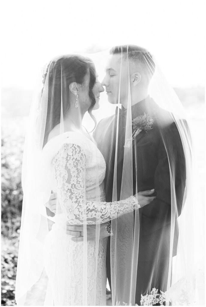 Bride and groom under a veil, close together.