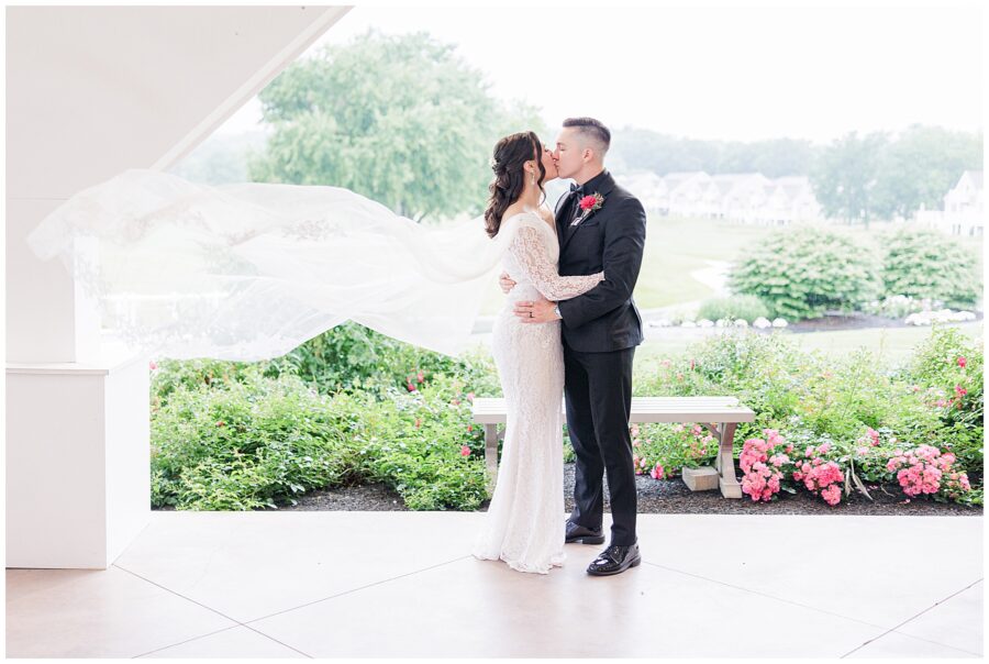 Bride and groom kissing with the bride’s veil flowing.