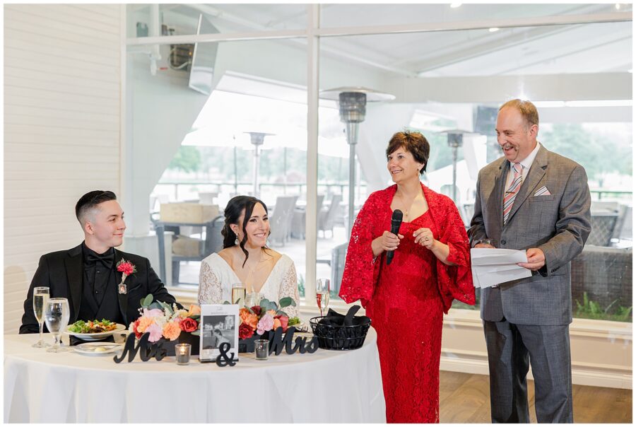 Bride and groom listening to speeches with two guests standing