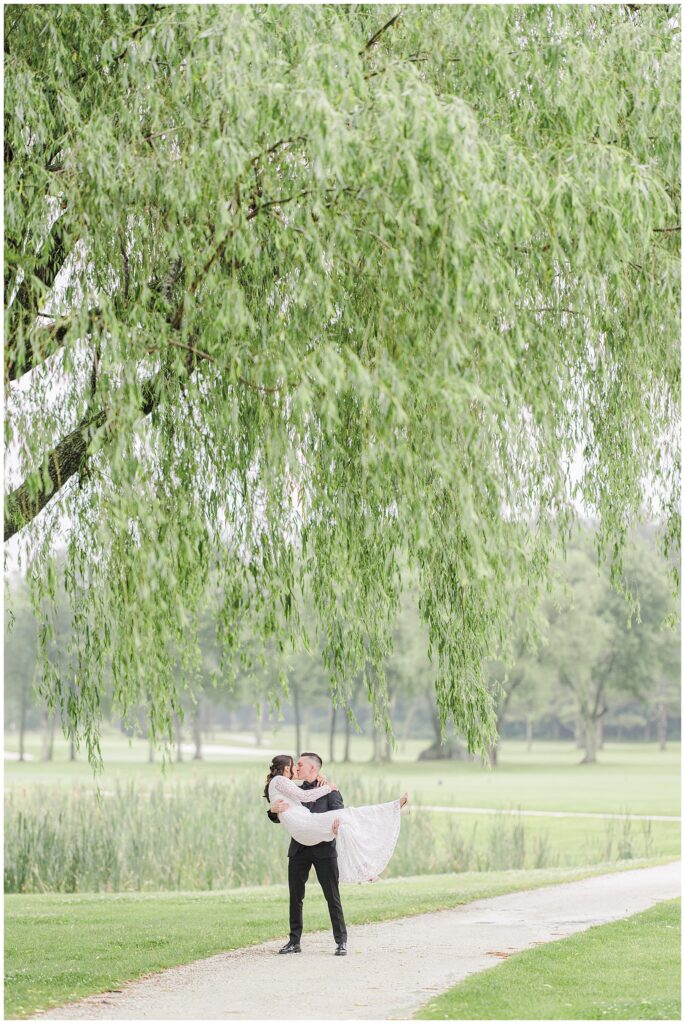 Groom lifting the bride, kissing her.