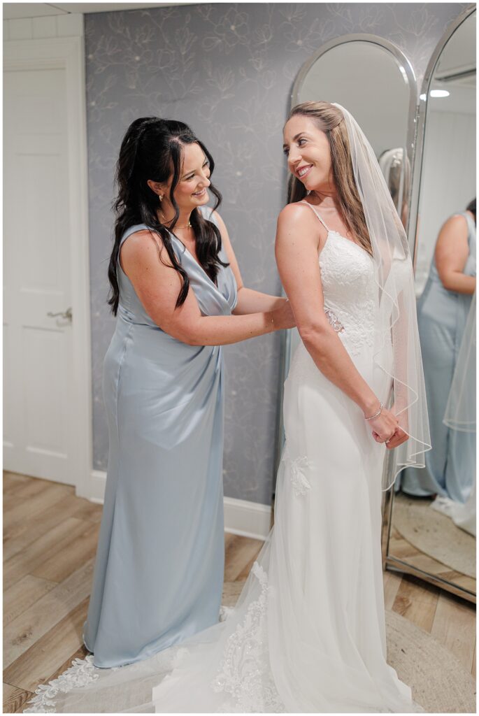 Bridesmaid helping bride with dress at Wychmere Beach Club.