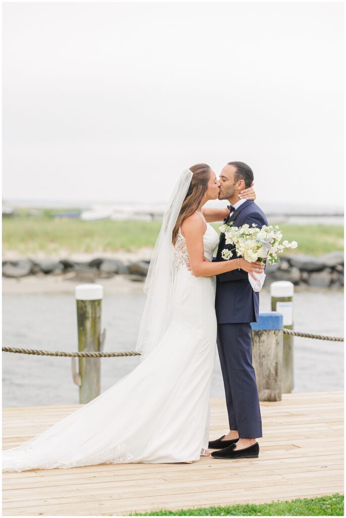 Bride and groom kissing by the water.