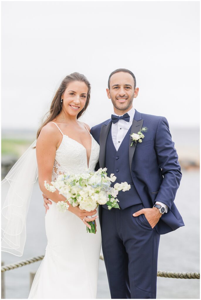 Bride and groom posing with bouquet at Wychmere Beach Club.