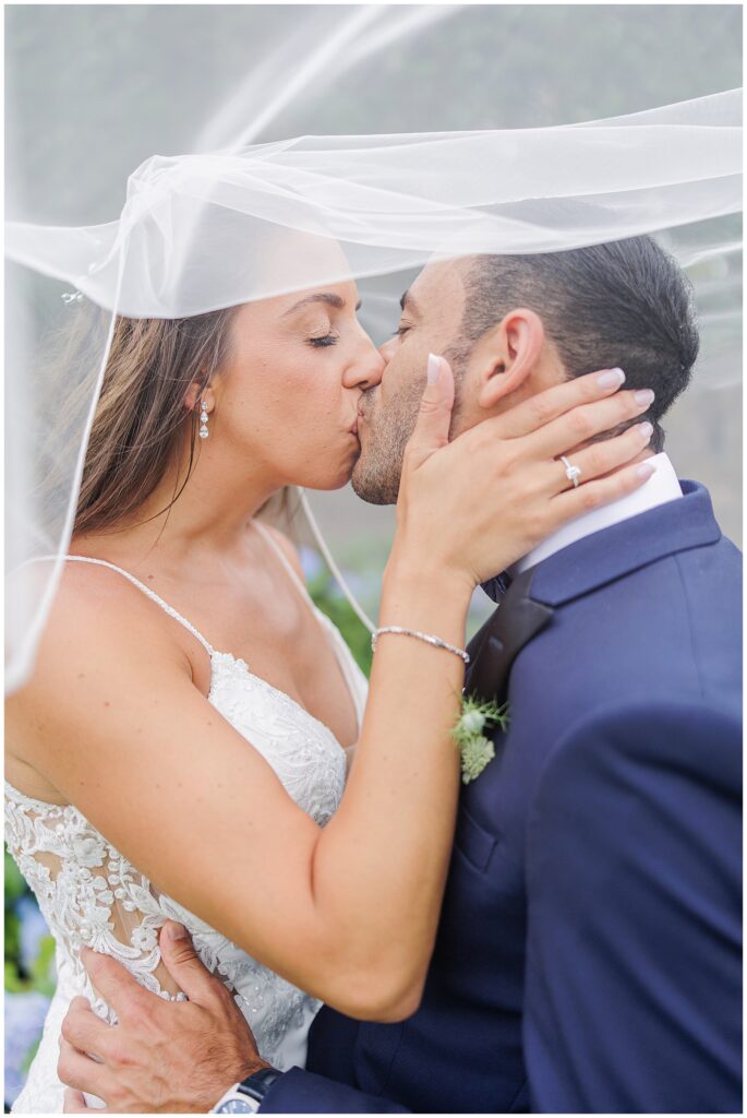 Bride and groom kissing, bride’s hand on groom’s cheek.