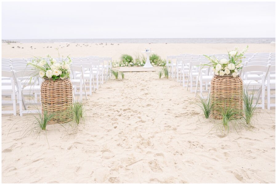 Beach wedding setup with white chairs and flower arrangements at the Wychmere Beach Club.