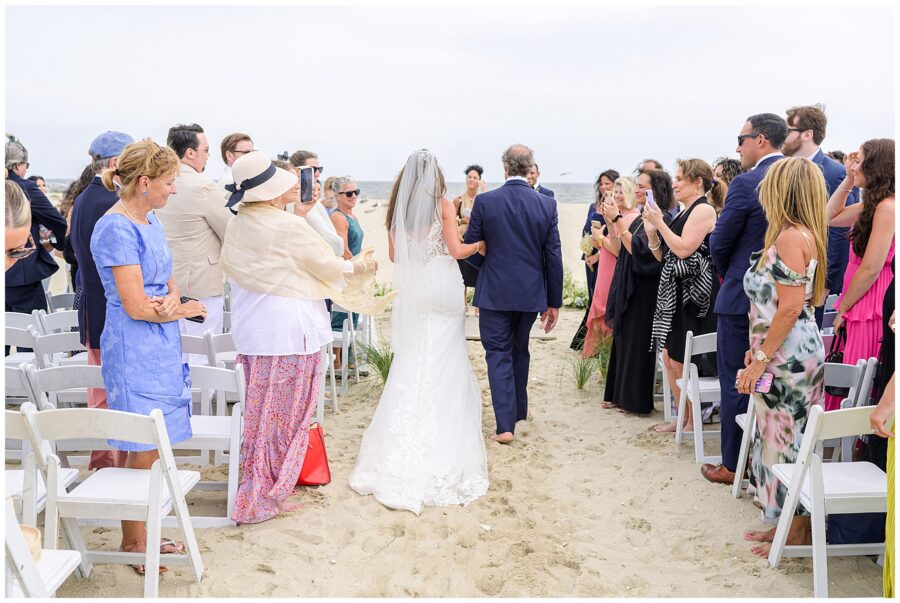 Bride walking down the aisle with her father as guests stand at the Wychmere Beach Club.