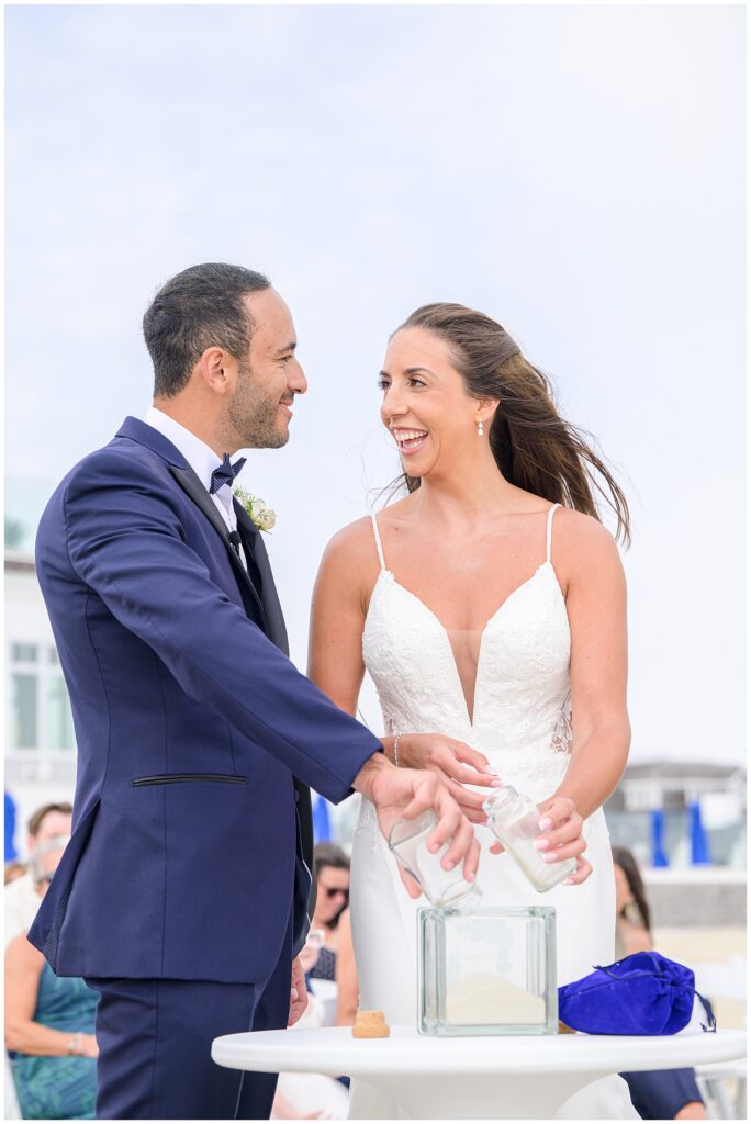 Bride and groom smiling during sand ceremony at the Wychmere Beach Club.