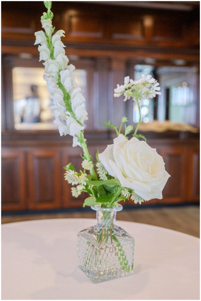 White rose and flower arrangement in a glass vase at the wedding reception.