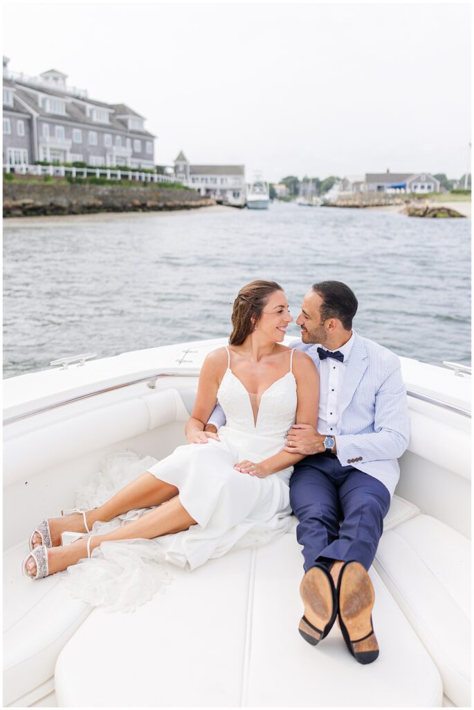 Bride and groom sitting on a boat, embracing, with the marina in the background.