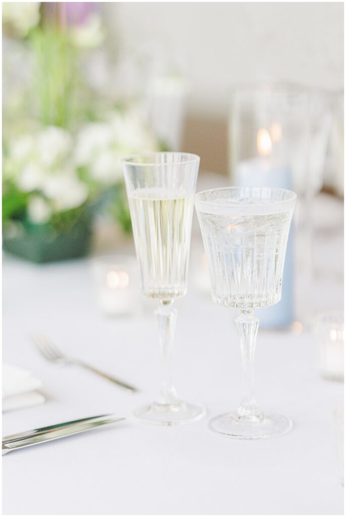 Crystal glasses of champagne and water on a wedding reception table.