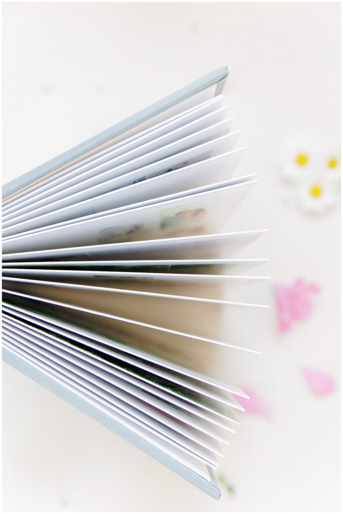 Side view of a partially open wedding album with white pages and a light blue cover.