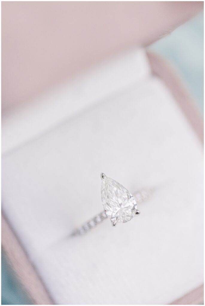 A detailed close-up of the pear-shaped diamond engagement ring in an open box with a velvet lining.