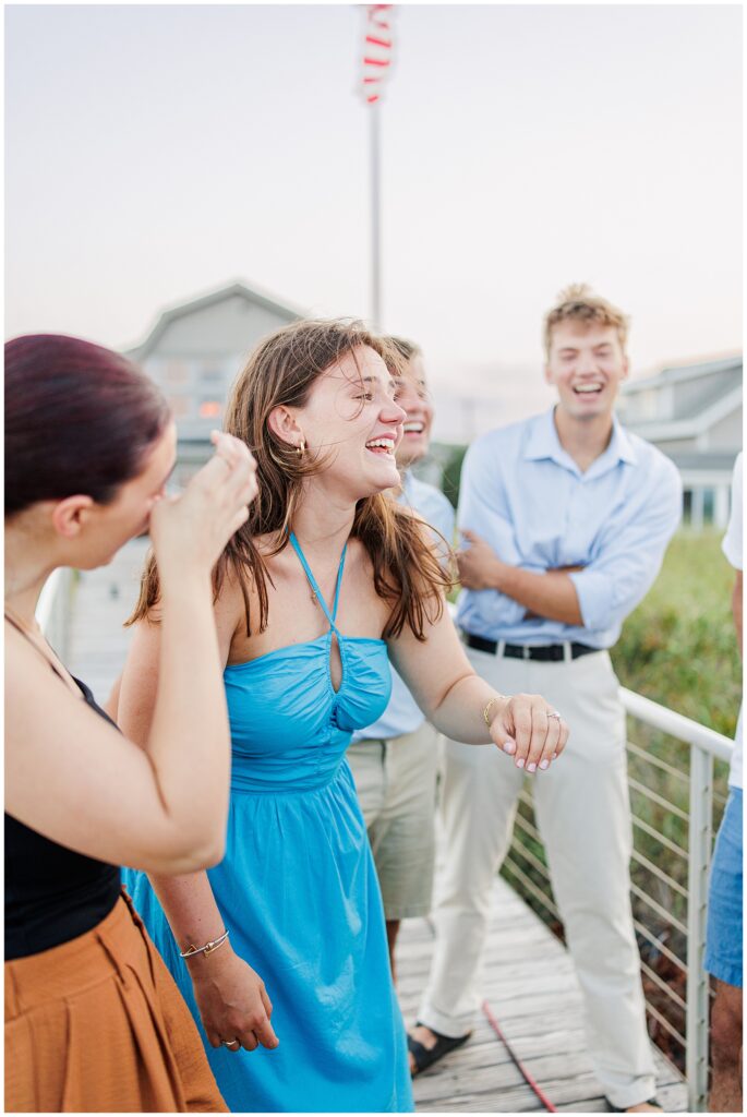 The woman laughs with friends and family on the boardwalk, celebrating the proposal.