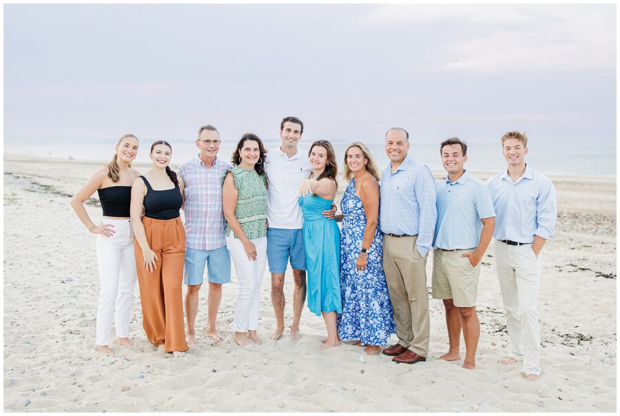 Group photo of the couple and their family standing on the beach in Sandwich, MA.