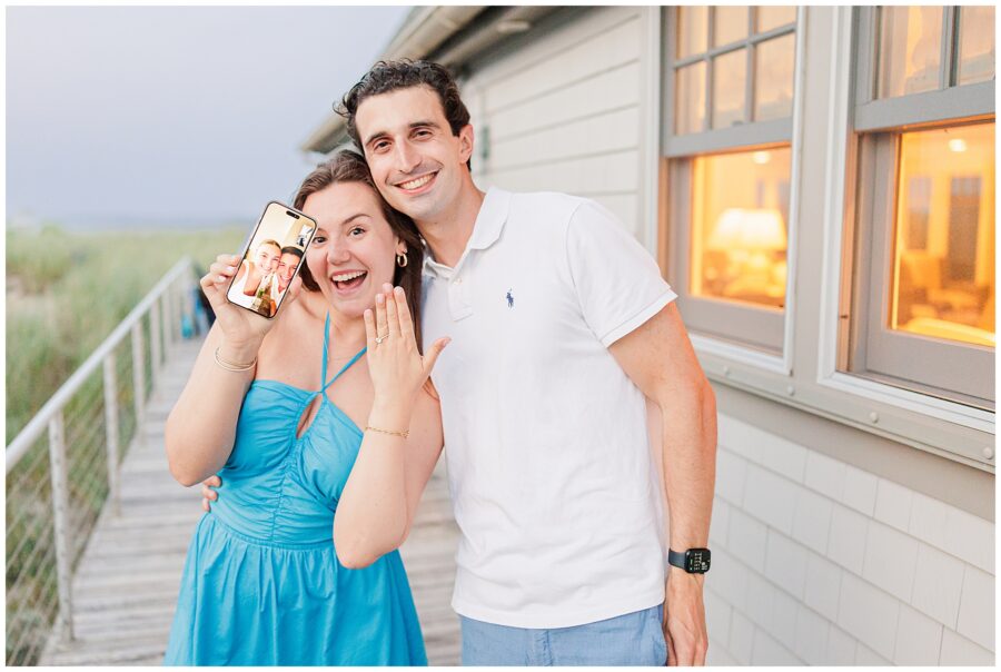 The newly engaged couple smiles, holding up a phone video call, showing off the engagement ring in Sandwich, MA.