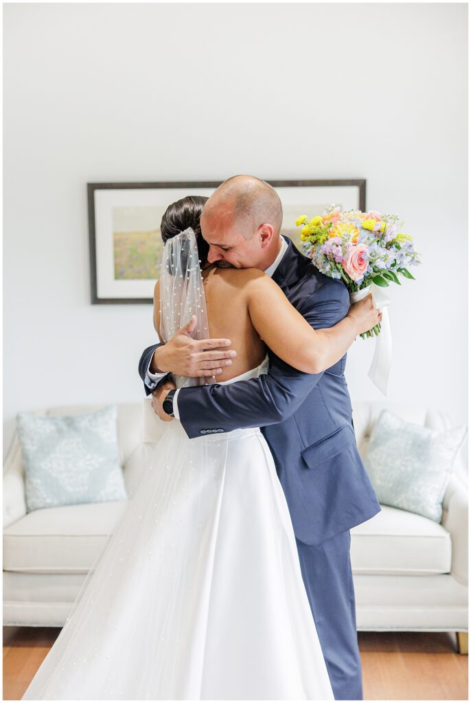 Bride and her father hugging tightly during a first look at Pembroke Pines Country Club in Pembroke, NH. The bride holds a pastel bouquet of roses and hydrangeas.