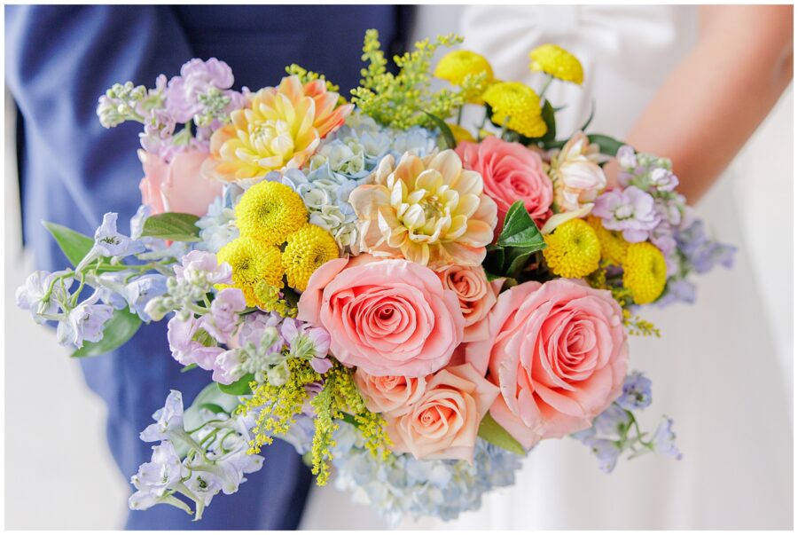 Close-up of the bride’s bouquet, featuring pink roses, yellow flowers, and blue accents, taken at Pembroke Pines Country Club in Pembroke, NH.