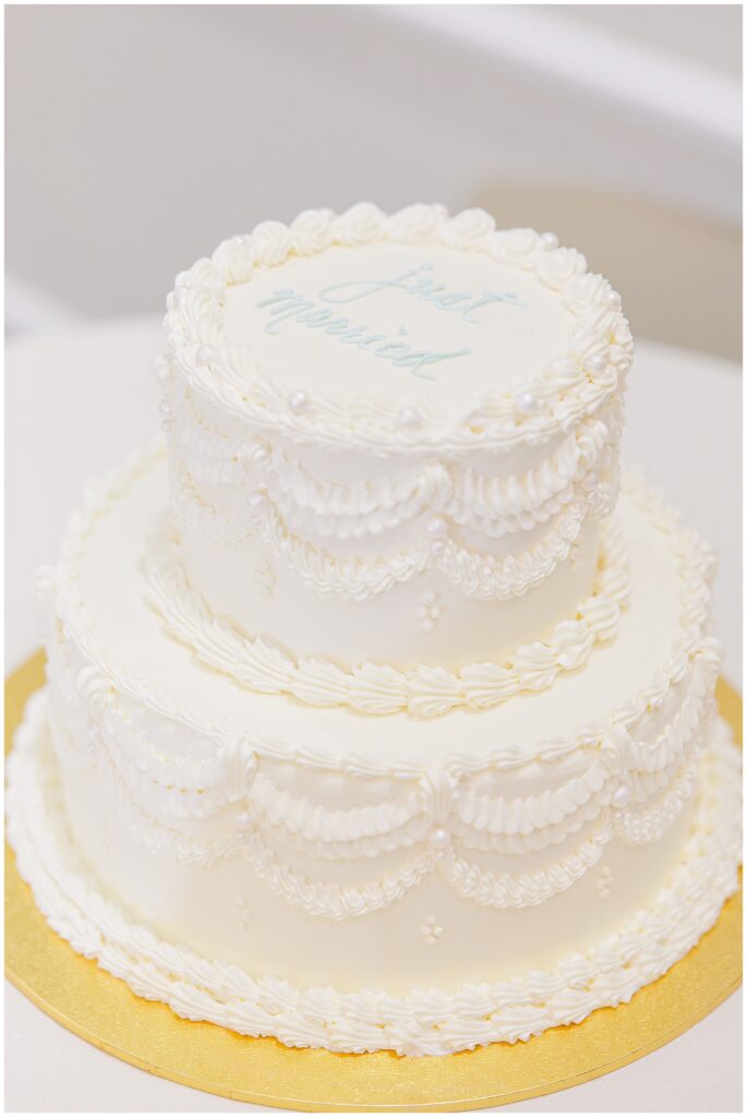 A two-tier white wedding cake with intricate piped designs and “Just Married” written on top, displayed at Pembroke Pines Country Club in Pembroke, NH.